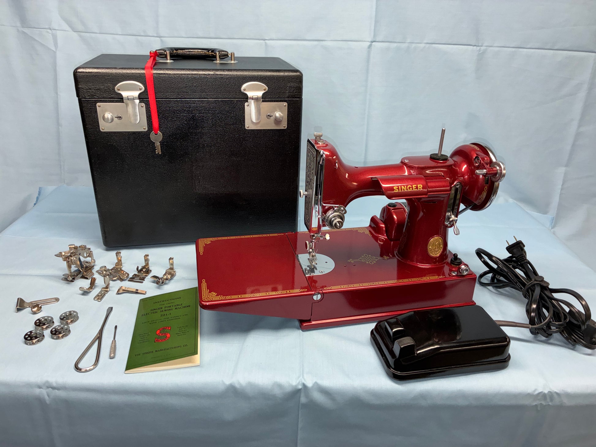 Vintage red sewing machine with accessories on a white background